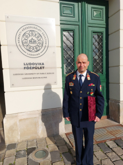 A fotón Jackovics Péter a Ludovika főépületének bejáratánál, kezében a díszoklevél