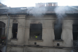 Tűzoltók dolgoznak a XI. kerületi Kruspér utcai társasház tüzénél, miközben az ablakokon dől ki a füst