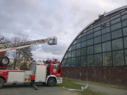 Megbontott tetejű csarnok, a kép bal oldalán magasból mentő jármű