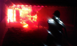 Egy tűzoltó oltja a teljes terjedelmében égő családi házat